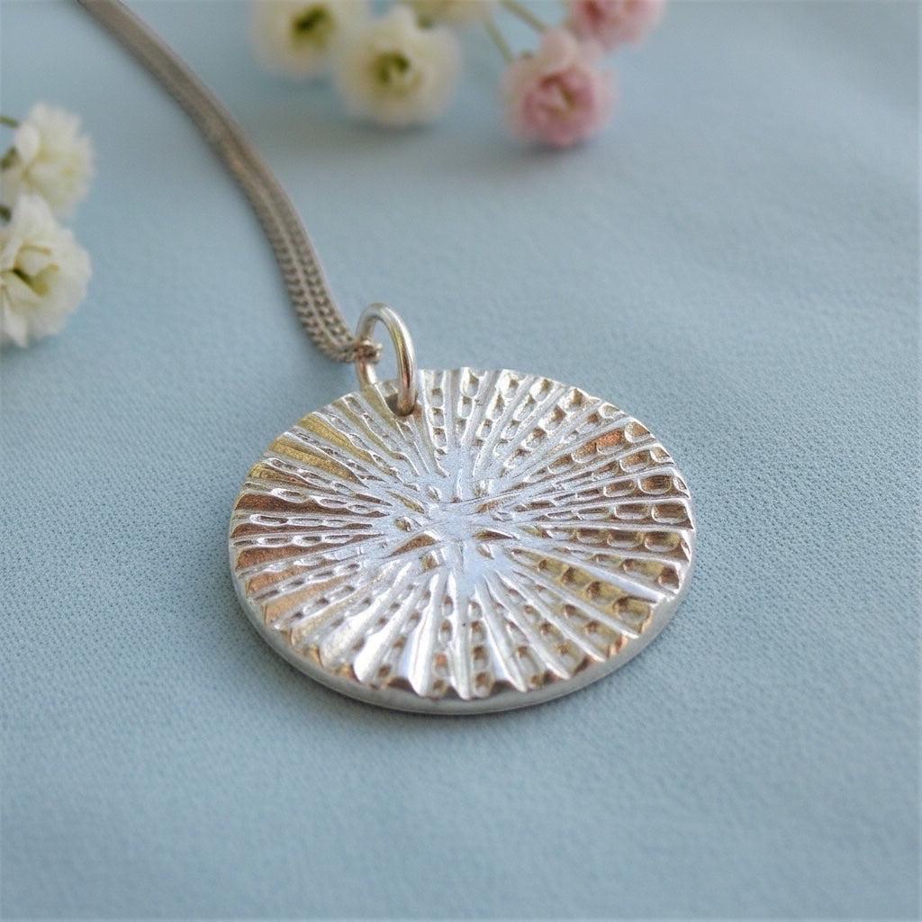 Blue Dragonfly Creations fine silver round pendant necklace with textured sunburst design on a sterling silver chain.