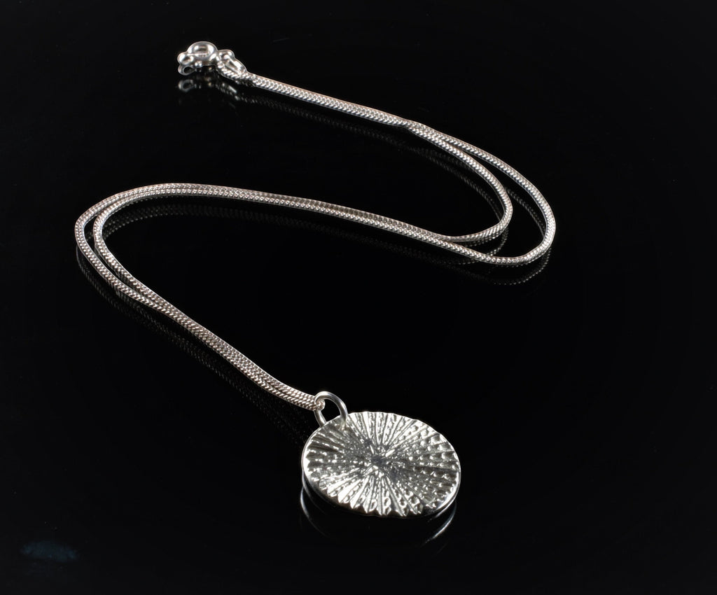 Blue Dragonfly Creations fine silver round pendant necklace with textured radiating lines on a sterling silver chain.