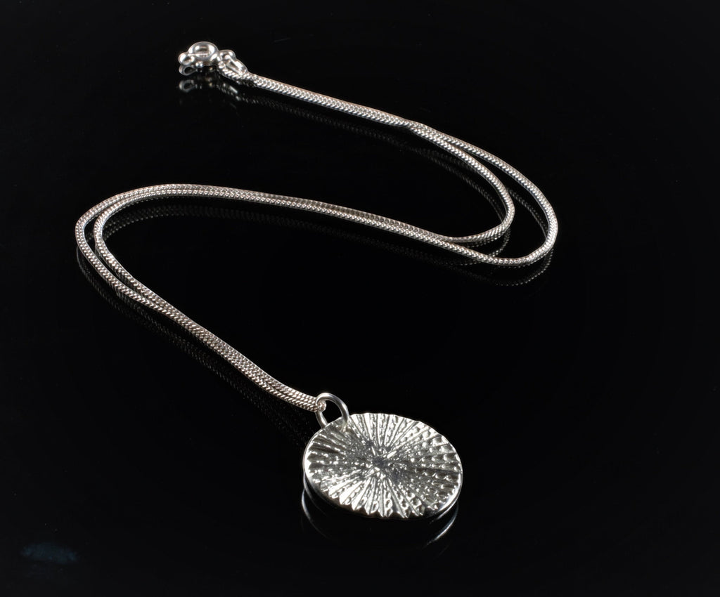 Blue Dragonfly Creations fine silver round pendant necklace with textured radiating lines on a sterling silver chain.