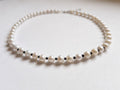 Blue Dragonfly Creations freshwater pearl necklace with white pearls and faceted black beads on a white background.