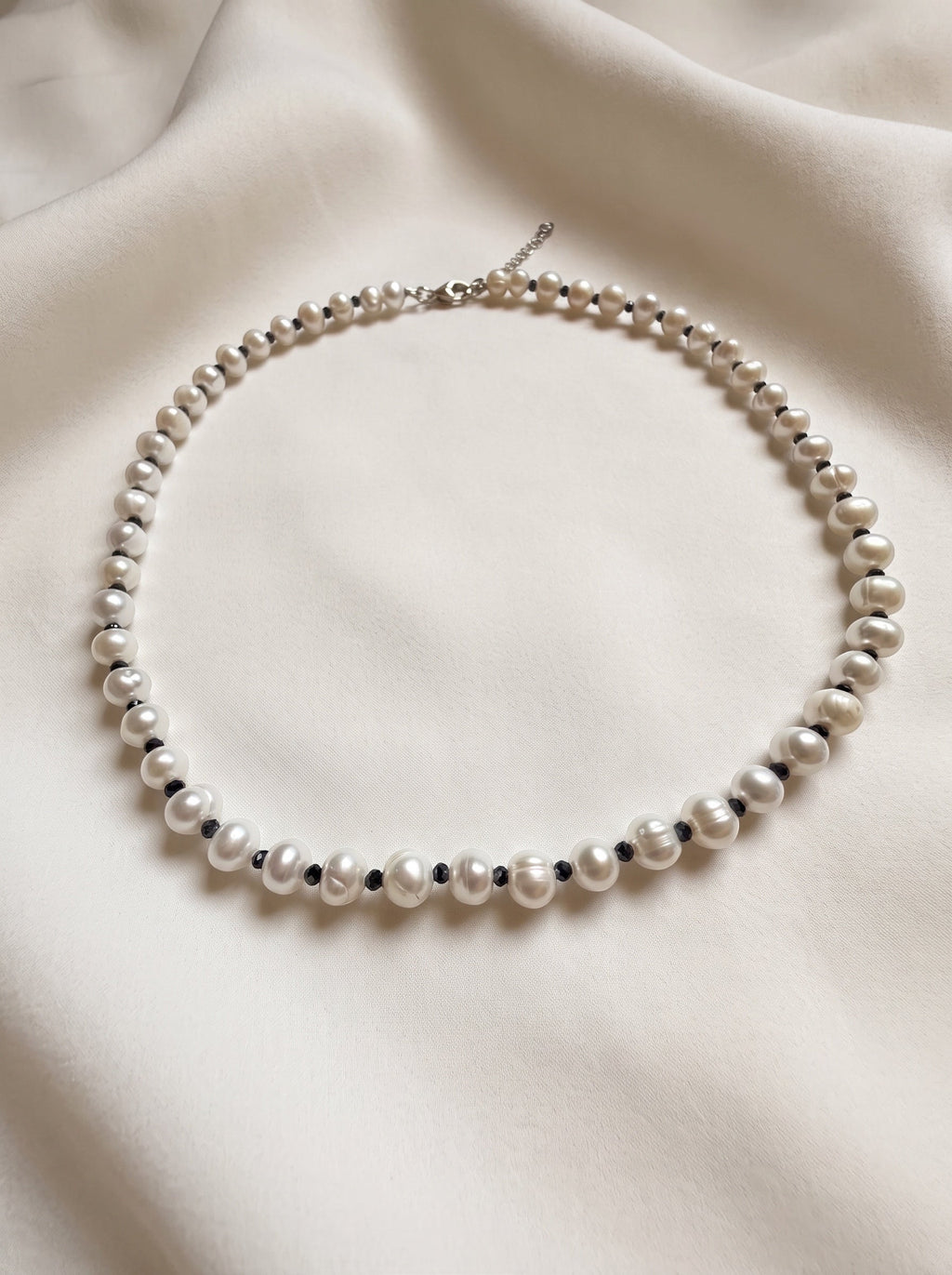 Blue Dragonfly Creations freshwater pearl necklace with faceted black beads and sterling silver clasp on white fabric