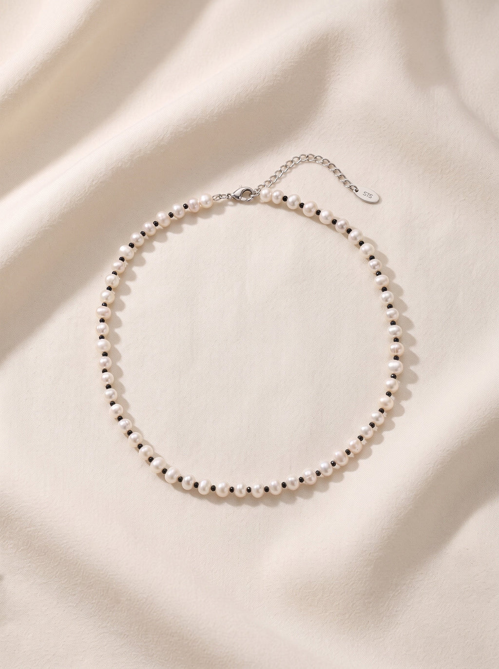 Blue Dragonfly Creations freshwater pearl necklace with black beads and sterling silver clasp on cream fabric