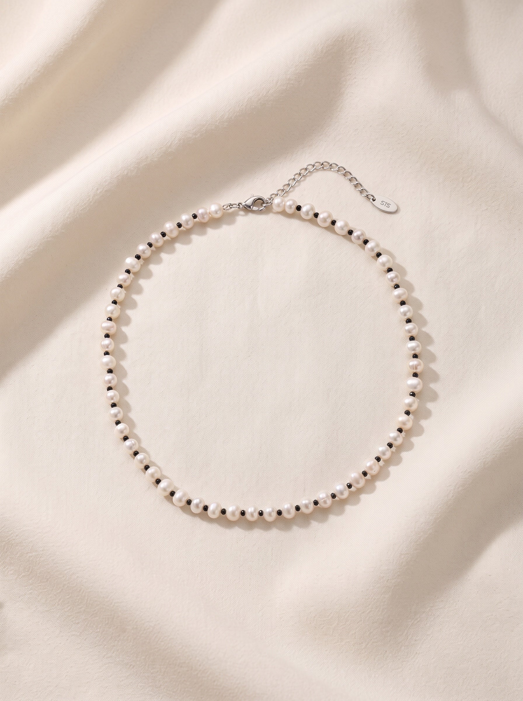 Blue Dragonfly Creations freshwater pearl necklace with black beads and sterling silver clasp on cream fabric