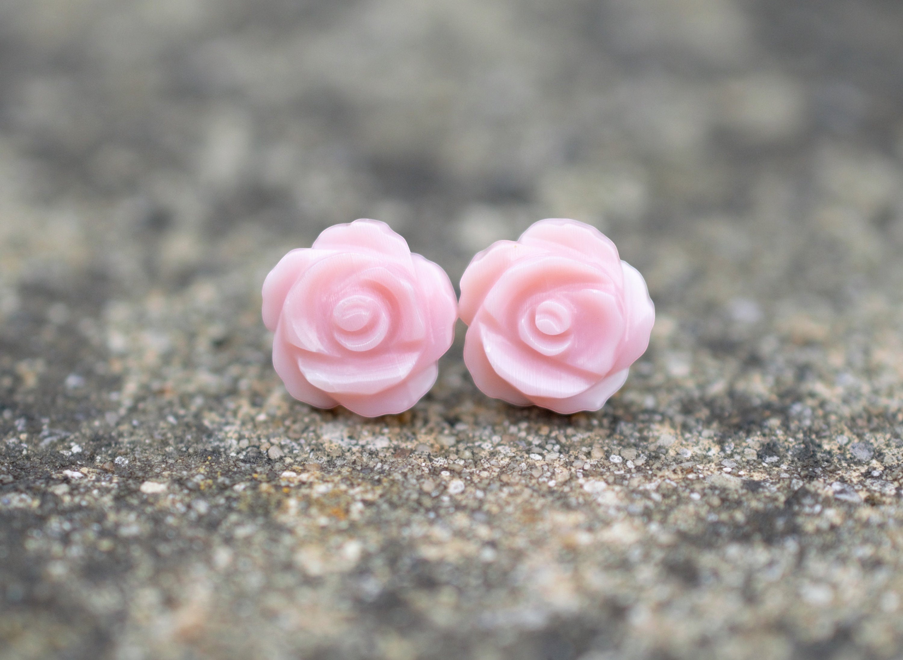 Blue Dragonfly Creations pink carved shell rose flower stud earrings with sterling silver backs on a stone surface