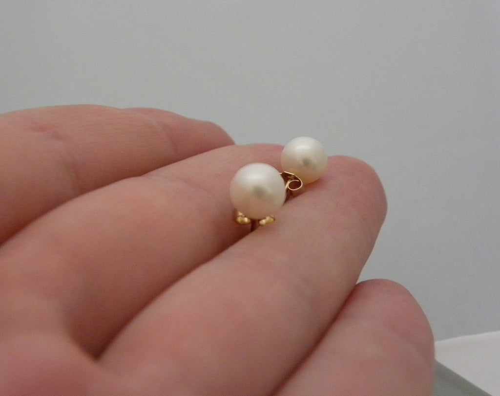 Blue Dragonfly Creations classic round pearl stud earrings with gold-tone posts held in a hand