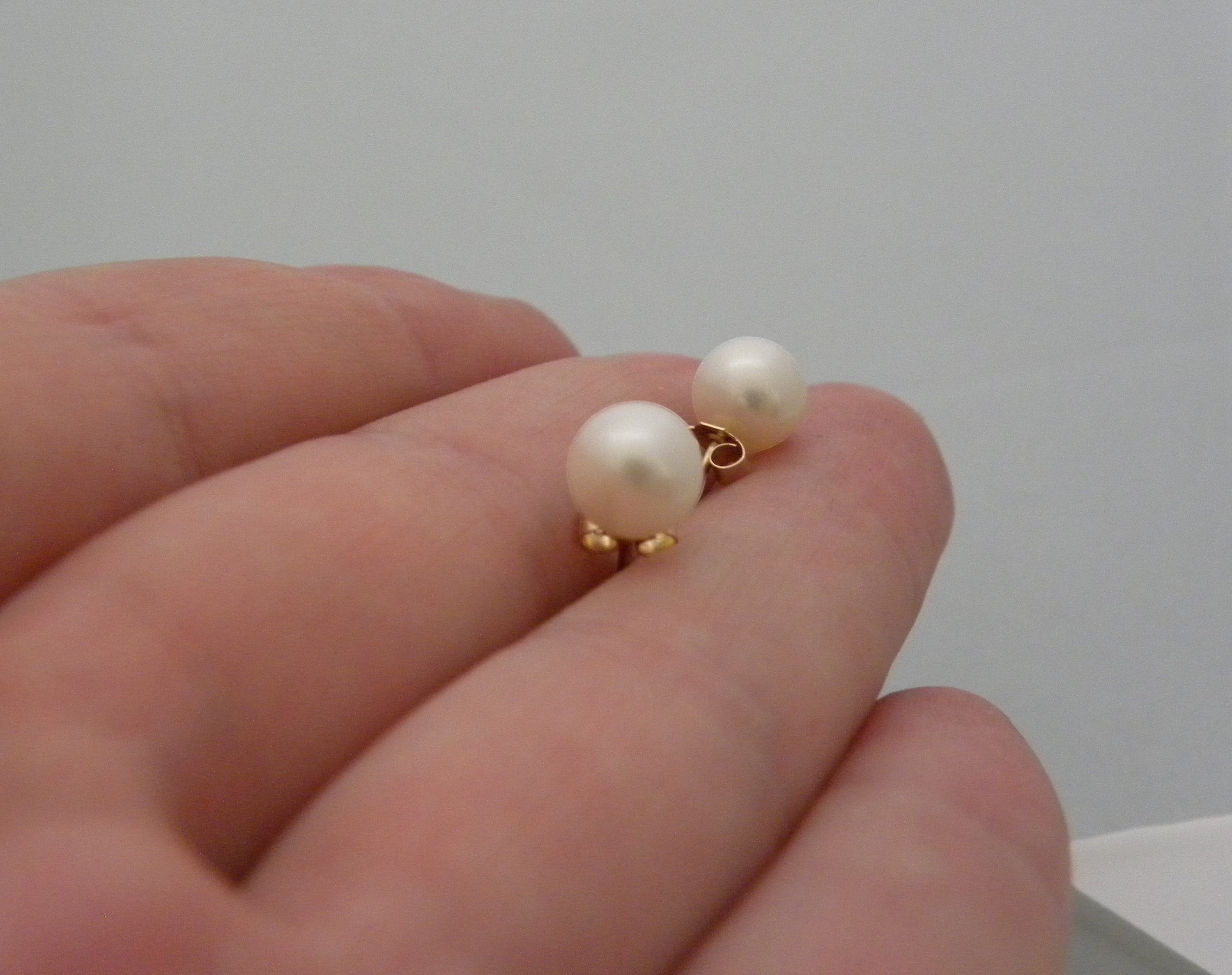 Blue Dragonfly Creations classic round pearl stud earrings with gold-tone posts held in a hand