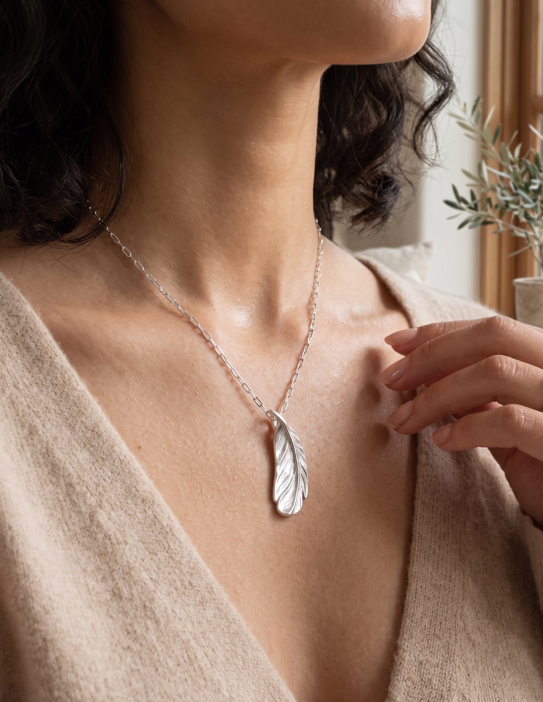 Blue Dragonfly Creations fine silver feather pendant necklace worn by a woman in a beige top