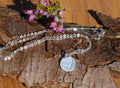 Blue Dragonfly Creations fine silver heart pendant necklace on a sterling silver chain resting on tree bark and heather